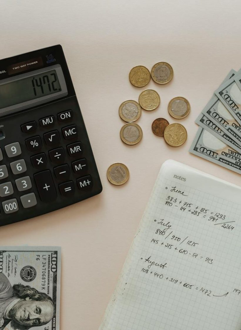 Black Calculator beside Coins and Notebook